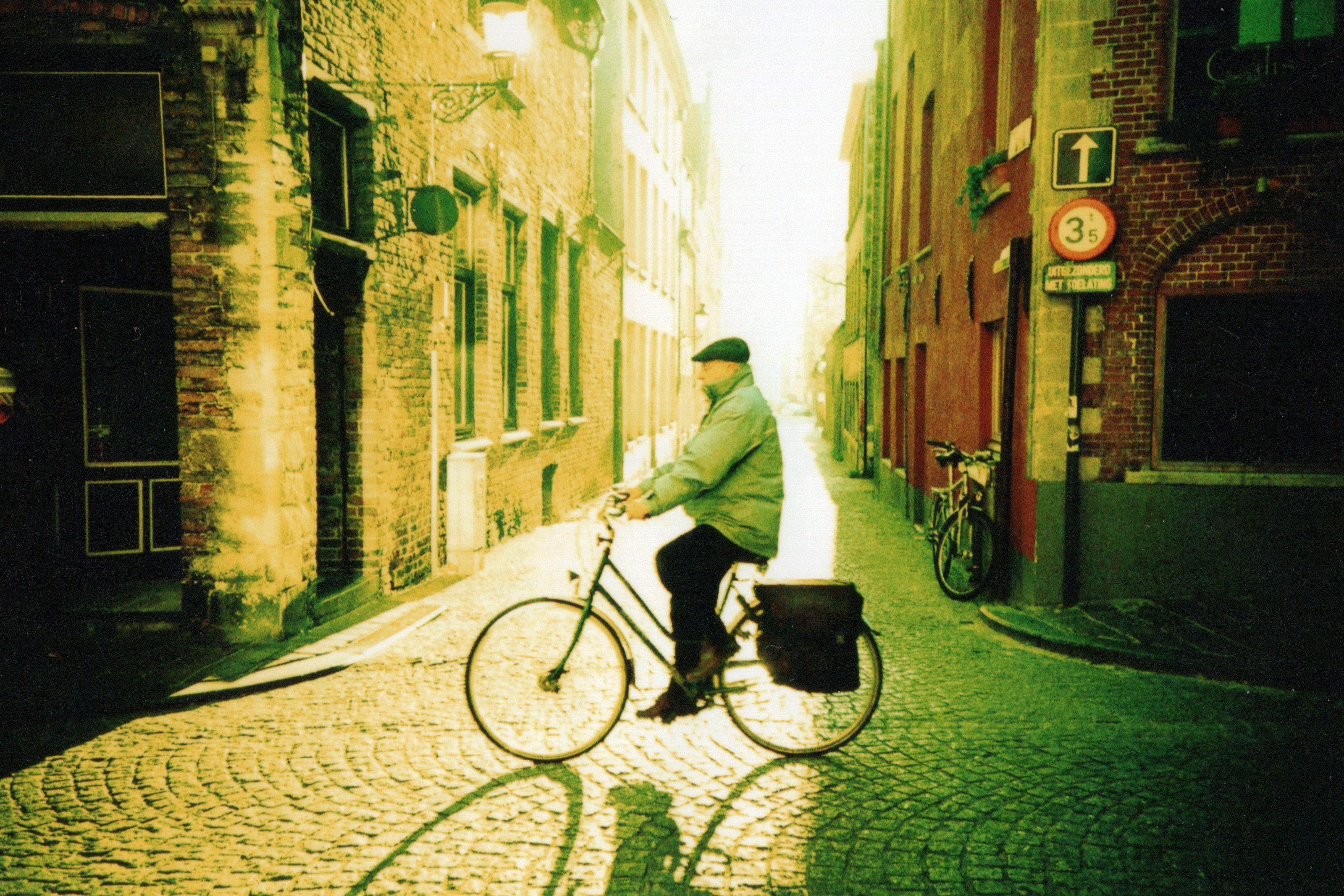 man in white hoodie riding on bicycle on street during daytime